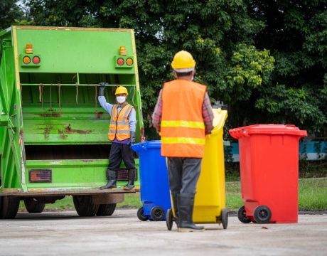 Garbage collection service,Rubbish cleaner man in a uniform working together on emptying dustbins for trash removal with truck loading waste and trash bin,Recycling concept.